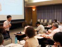 福島県立医科大学での講義中、講師が参加者に向けて説明している様子。受講者はメモを取りながら聴講している。
