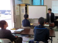 福島県立医科大学の教室で、講師が学生に向けて説明を行っている様子。学生たちは真剣に聞き入っている。