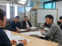 福島県立医科大学の会議室で、数人の参加者が資料を見ながら話し合っている様子。