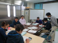 福島県立医科大学の会議室で、数人の人々が資料を見ながら話し合っている様子。