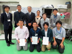 福島県立医科大学の職員と学生が集まり、表彰状を持って記念撮影している様子。