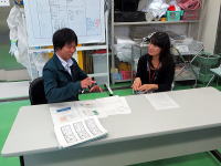 医療に関する話し合いをしている男女がテーブルを囲んでいる様子。背景には医療関連の資料や器具が見える。