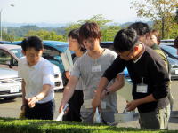 福島県立医科大学の学生たちが、屋外で何かを手に持ちながら作業をしている様子。