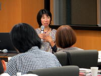 講演を行う女性が話している様子。参加者が聴講している会議室の風景。