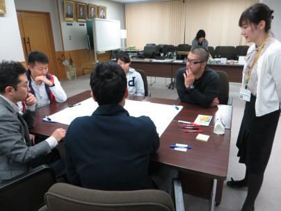 放射線災害に備えた研修中の受講者たちが、テーブルを囲んで意見を交わしている様子。