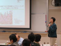 医科大学の講義でプレゼンテーションを行う女性講師と聴衆の様子。