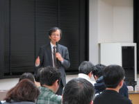 福島県立医科大学で講演を行う男性と聴衆の様子。
