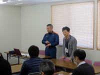 福島県立医科大学の会議室で、講演を行う男性二人と参加者の様子。