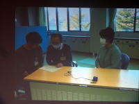 福島県立医科大学の教室で、マスクを着用した3人の学生がテーブルを囲んで話し合っている様子。