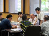 福島県立医科大学の会議室で、数人の男性が資料を囲んで話し合っている様子。