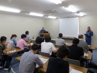 福島県立医科大学の教室で行われている講義の様子。受講生が座って講師の話を聞いている。