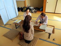 医療面接を受ける女性と医療従事者が対話している様子。和室の畳の上で行われている。