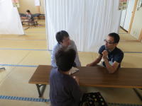 福島県立医科大学の施設内で、テーブルを囲んで話し合う3人の男女の様子。