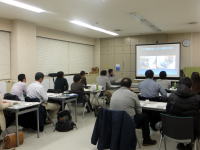 福島県立医科大学の教室で、受講生が講義を受けている様子。スクリーンにはプレゼンテーションが映し出されている。