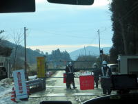 福島県立医科大学近くの道路で、作業員が交通を制御している様子。背景には山々が広がる。