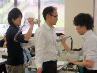 医療技術の実習中、白衣を着た学生が相互に器具を使っている様子。