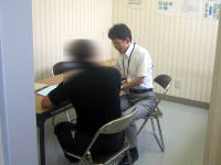 健康相談を行う医療従事者と相談者がテーブルを挟んで向かい合っている様子。