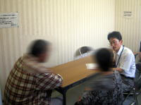 健康相談を受ける男女と医療従事者がテーブルを囲んでいる様子。