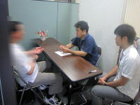 健康相談を受ける3人の男性がテーブルを囲んでいる様子。