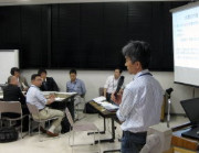 第44回医学教育セミナーで講演を行う男性と参加者たちが議論している様子。