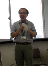 第44回医学教育セミナーで講演する男性が、資料を手に持ちながら話している様子。背景には窓があり、明るい室内の雰囲気。
