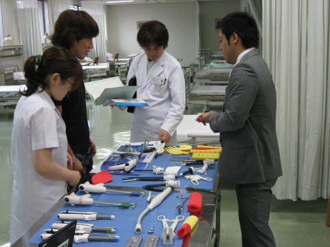 医療器具を前にした学生たちが、シミュレーターを使ったデモを行いながら話し合っている様子。
