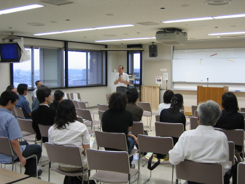 テュートリアルコースの発表を行う講師と、聴講する学生たちが集まる教室の様子。