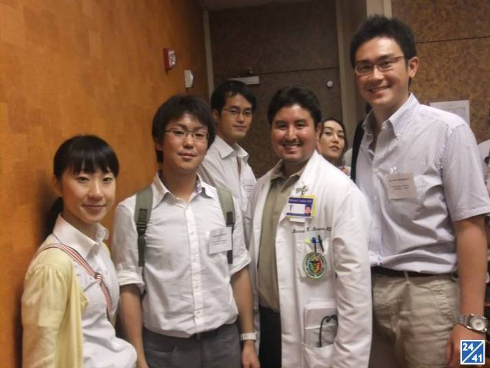 医療関係者と思われる若者たちが集まり、笑顔でポーズをとっている様子。背景には病院の内部が見える。