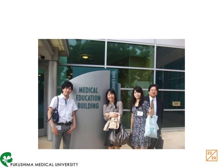 福島県立医科大学の医療教育棟前で記念撮影をする4人の男女。