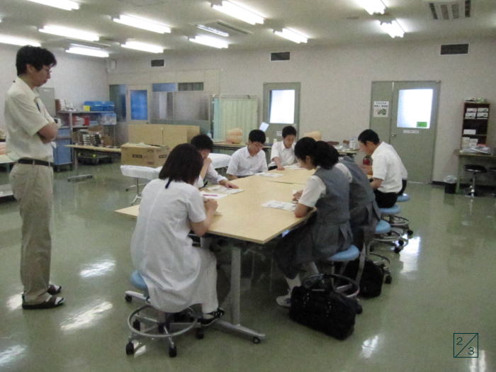 郡山第二中学校の教室で、3年生の生徒たちがテーブルを囲んで学習している様子。教師が見守る中、真剣に取り組んでいる。