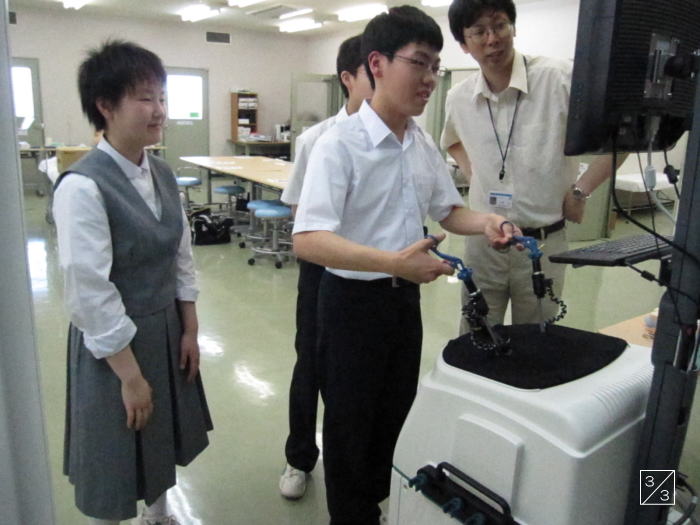 郡山第二中学校の生徒が医療機器を操作し、教員が見守る学校見学の様子。