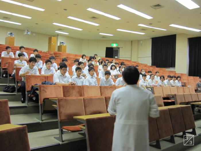 福島成蹊中学校の教室で、白衣を着た講師が生徒たちに授業を行っている様子。