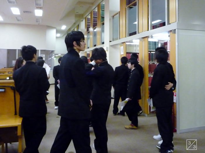 福島県立磐城高等学校の図書館で、黒い制服を着た生徒たちが見学している様子。