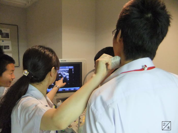 学校見学中の郡山第二中学校の生徒たちが、医療機器の操作を学んでいる様子。