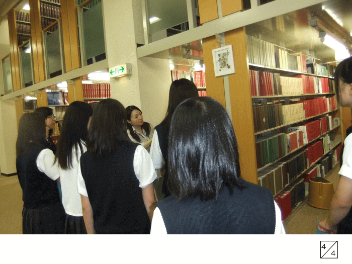 福島県立光南高等学校の図書館で、1年生の生徒たちが本棚を見ながら説明を受けている様子。