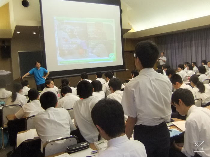 学校見学中の会津学鳳中学校の生徒たちが、講義を受けている様子。前方にはプレゼンテーションが映し出されている。