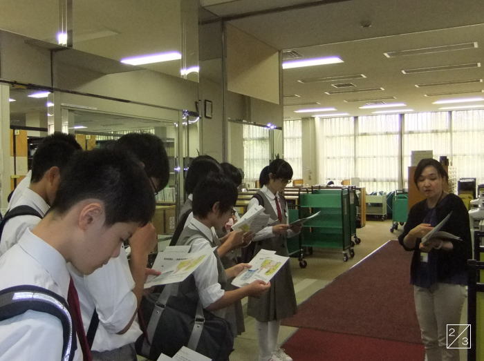 学校見学中の安積第二中学校の3年生が、教員の説明を受けながら資料を手にしている様子。