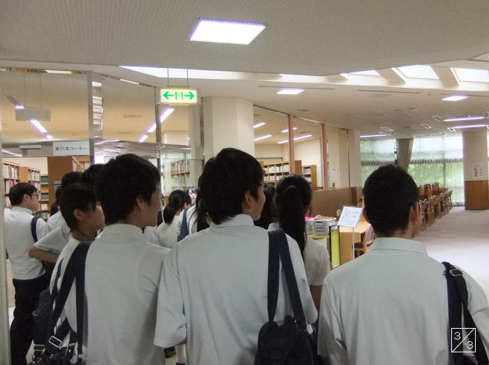 福島成蹊中学校の3年生が学校見学中、図書館の前で後ろ向きに立っている様子。