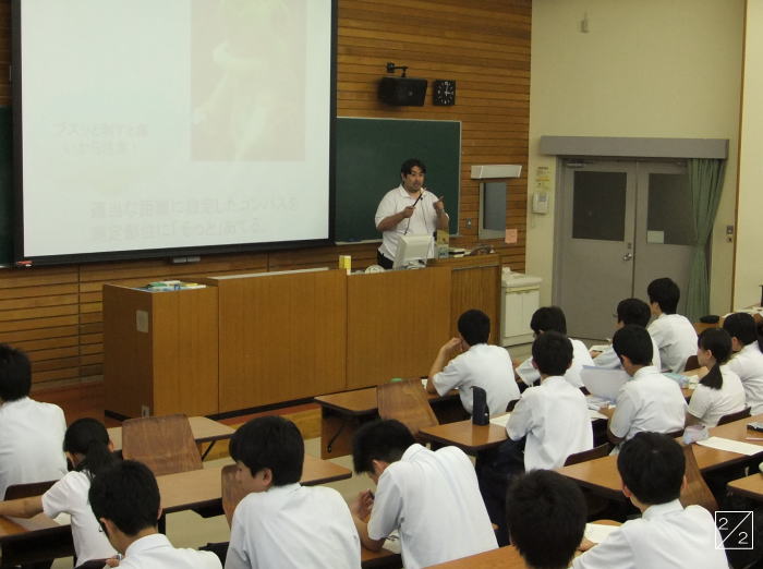 学校の教室で講義を行う講師と、前方を向いている生徒たちの様子。