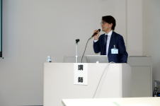 腹部エコーセミナーで講演を行う男性が、マイクを持って話している様子。