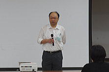 心エコーセミナーで講演を行う男性がマイクを持ち、聴衆に向かって話している様子。