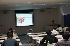 腹部エコーセミナーの講義中、スライドに腹部の図が映し出されている教室の様子。受講者が座っている。