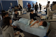 腹部エコーセミナーでの実習風景。受講生が患者役にエコー検査を行っている様子。
