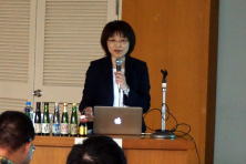 心エコーセミナーで講演を行う女性が、マイクを持ち、パソコンの前で話している様子。