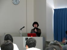 腹部エコーセミナーで講演を行う女性がマイクを持ち、参加者に向けて話している様子。