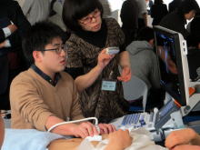 腹部エコーセミナーでの実習風景。学生がエコー装置を操作し、指導者が説明している様子。
