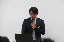腹部エコーセミナーで講演を行う男性が、マイクを持って話している様子。