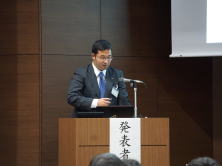 福島県地域医療症例検討会で発表する研修医の錫谷研先生が壇上でプレゼンテーションを行っている様子。
