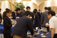 福島県地域医療症例検討会の参加者が交流する様子。ビジネススーツを着た人々がテーブルを囲んでいる。
