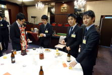 福島県地域医療症例検討会の参加者がテーブルを囲み、飲み物や料理を手にしている様子。